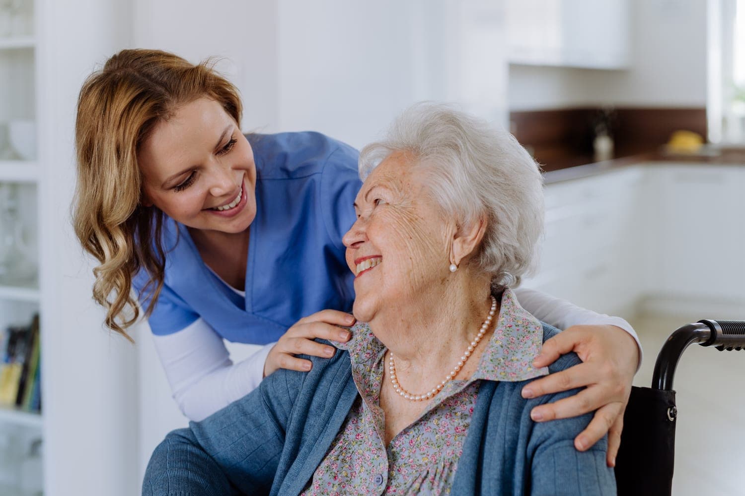 A home carer and an older woman smiling warmly together at home